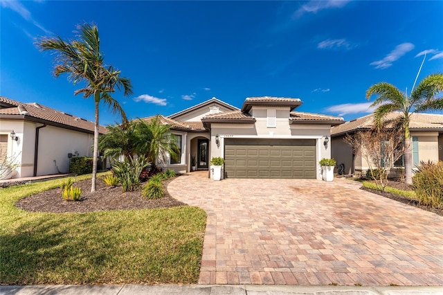 13077 Rinella St, Venice, FL 34293 - mediterranean / spanish-style house featuring stucco siding, a tile roof, a garage, and decorative driveway