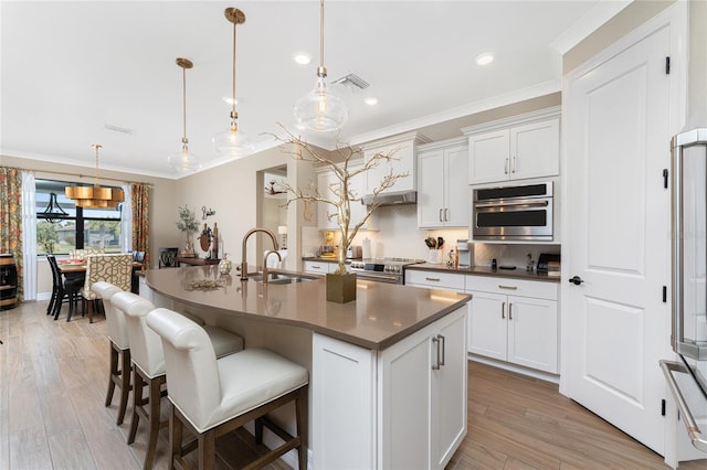 kitchen featuring appliances with stainless steel finishes, sink, hanging light fixtures, and an island with sink