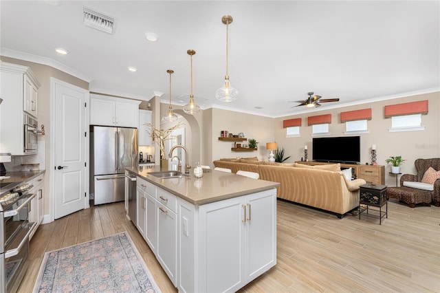 kitchen with sink, appliances with stainless steel finishes, decorative light fixtures, and white cabinets