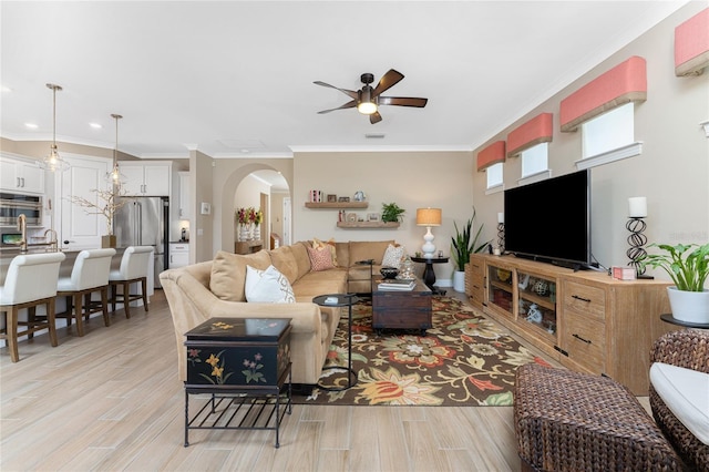 living room featuring ceiling fan, ornamental molding, and light hardwood / wood-style flooring