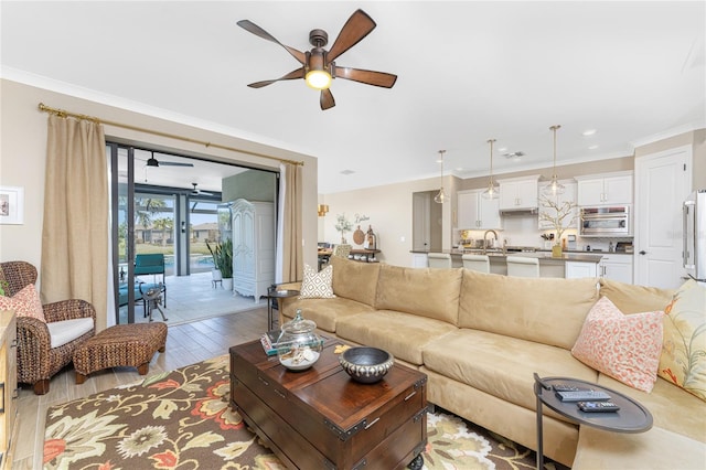 living room with sink, ceiling fan, ornamental molding, and light hardwood / wood-style flooring