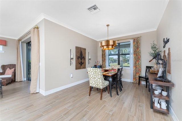 dining space with crown molding, light hardwood / wood-style flooring, and a notable chandelier