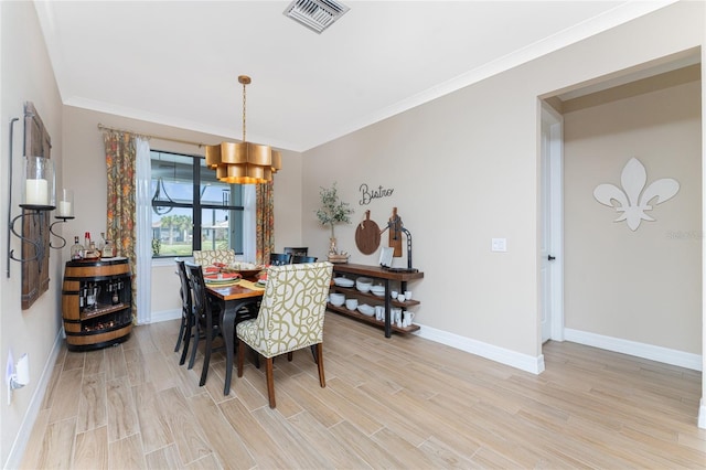 dining room featuring a notable chandelier, light hardwood / wood-style floors, and crown molding