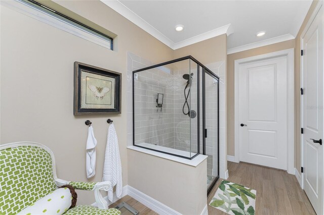 bathroom featuring ornamental molding, hardwood / wood-style floors, and a shower with shower door