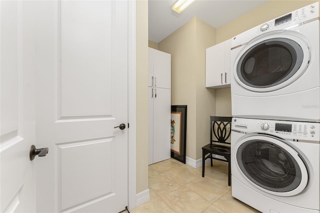 laundry room with cabinets, stacked washing maching and dryer, and light tile patterned flooring