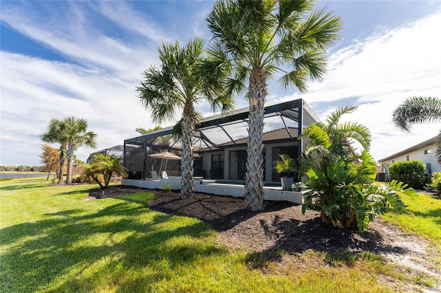 rear view of house with a yard and a lanai