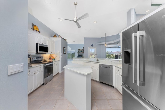 kitchen featuring appliances with stainless steel finishes, sink, a center island, decorative light fixtures, and white cabinets