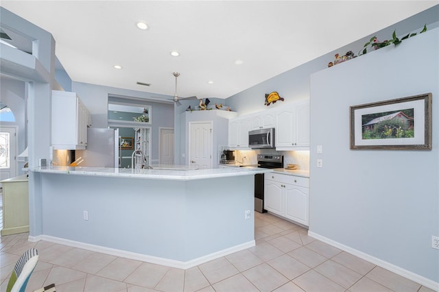 kitchen with appliances with stainless steel finishes, kitchen peninsula, white cabinets, and light tile patterned floors