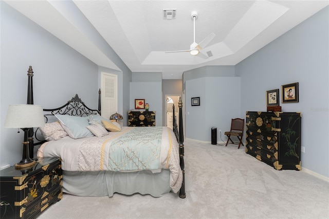 carpeted bedroom with a raised ceiling and ceiling fan