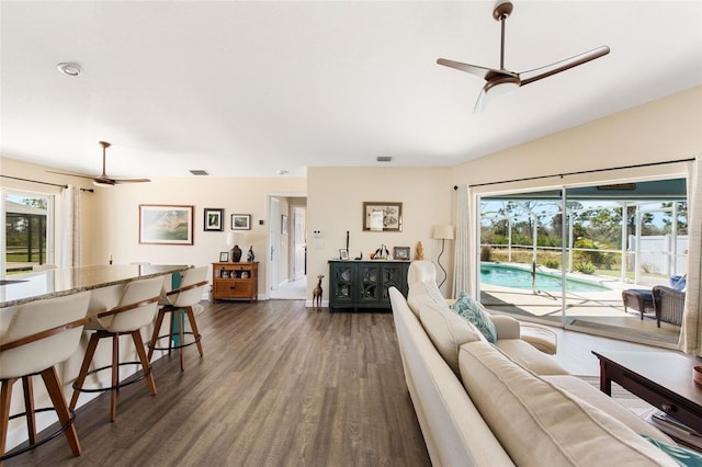 living room featuring a healthy amount of sunlight, ceiling fan, vaulted ceiling, and dark hardwood / wood-style flooring