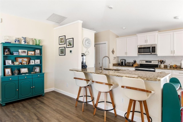 kitchen with appliances with stainless steel finishes, white cabinetry, and sink