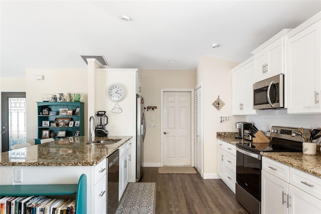 kitchen featuring white cabinetry, dark stone countertops, dark hardwood / wood-style floors, sink, and stainless steel appliances