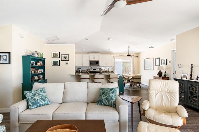 living room featuring sink, dark wood-type flooring, and ceiling fan