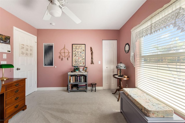 living area with light carpet and ceiling fan