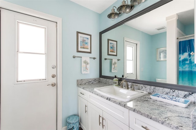 bathroom with vanity, toilet, and plenty of natural light