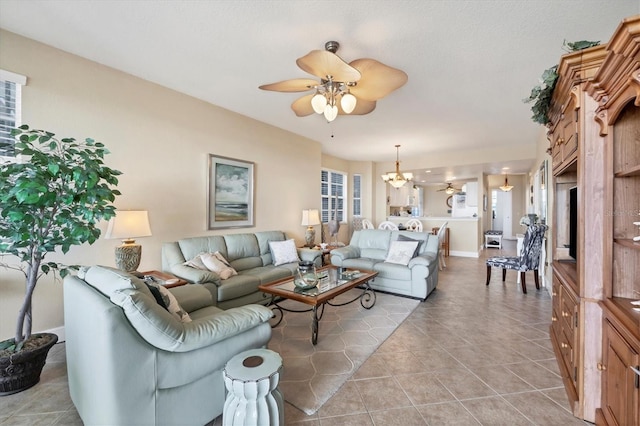 tiled living room featuring ceiling fan with notable chandelier and plenty of natural light