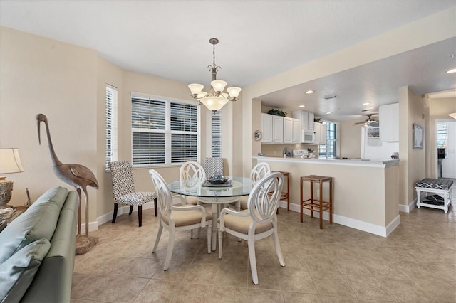 dining space with plenty of natural light, light tile patterned floors, and ceiling fan with notable chandelier