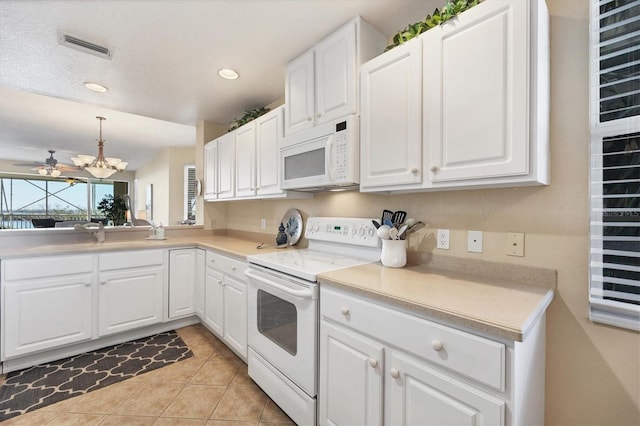 kitchen with white appliances, sink, light tile patterned floors, decorative light fixtures, and white cabinetry