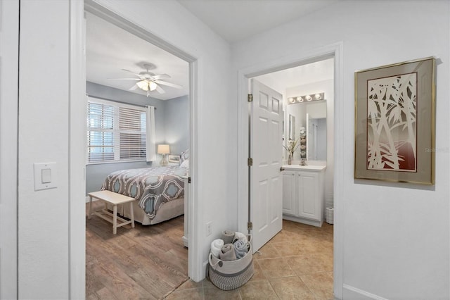 bedroom featuring ceiling fan, light wood-type flooring, and ensuite bathroom