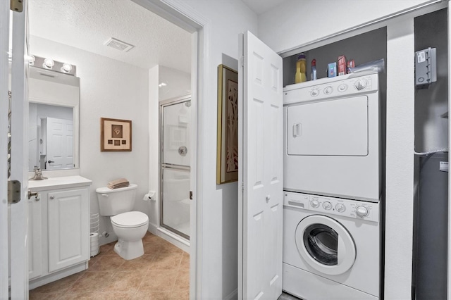 washroom with light tile patterned floors, a textured ceiling, and stacked washer and clothes dryer