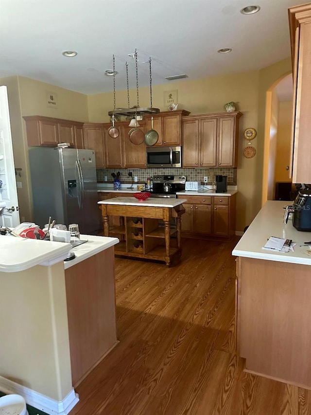 kitchen featuring hardwood / wood-style floors, a center island, stainless steel appliances, and backsplash