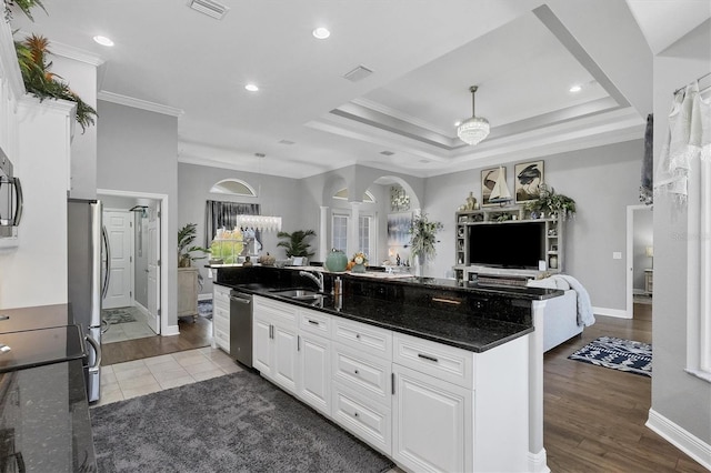 kitchen featuring sink, hardwood / wood-style floors, white cabinetry, stainless steel appliances, and dark stone countertops