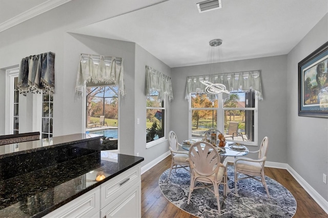 dining area featuring ornamental molding and dark wood-type flooring