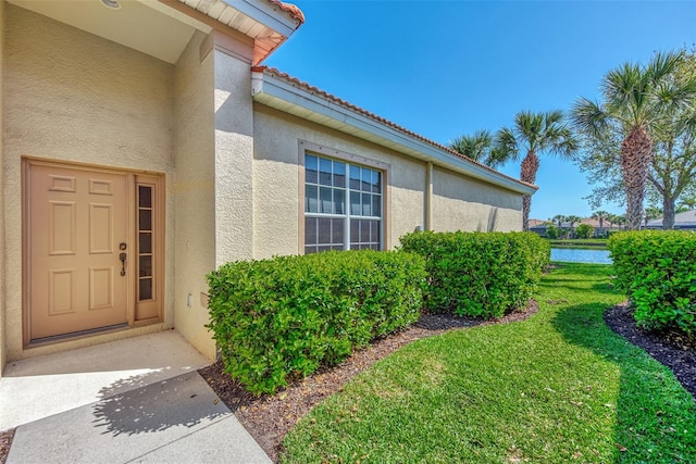 entrance to property with a water view and a yard