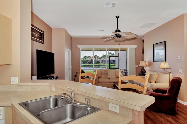 kitchen with dark hardwood / wood-style flooring, kitchen peninsula, sink, and ceiling fan