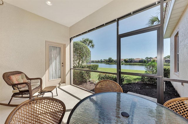 sunroom featuring a water view