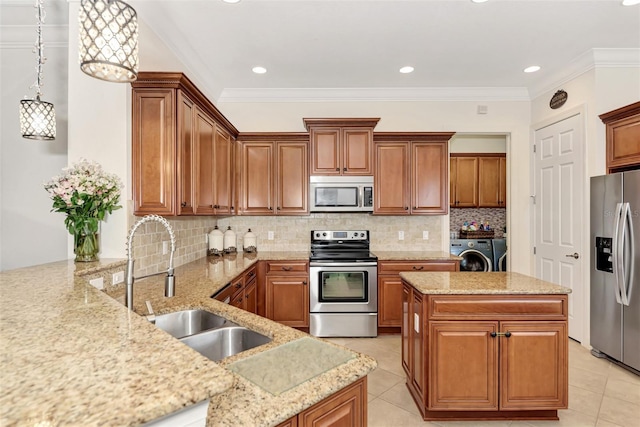 kitchen featuring sink, washer and clothes dryer, hanging light fixtures, stainless steel appliances, and kitchen peninsula