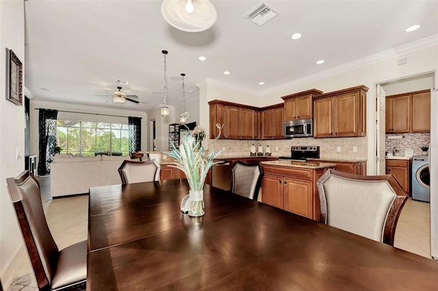 dining area featuring washer / clothes dryer, crown molding, light tile patterned floors, and ceiling fan