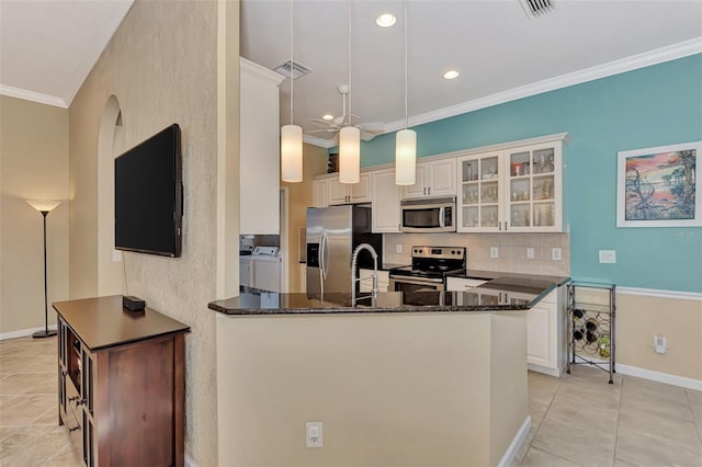 kitchen featuring white cabinetry, appliances with stainless steel finishes, decorative light fixtures, washing machine and dryer, and kitchen peninsula