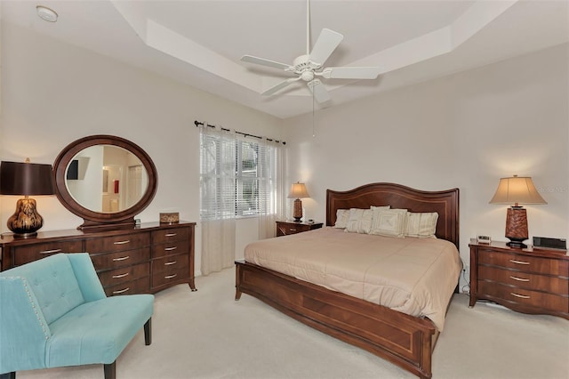 bedroom with a tray ceiling, light carpet, and ceiling fan