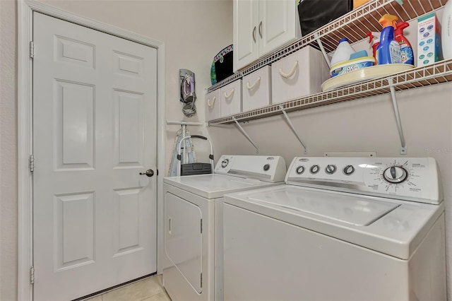 clothes washing area featuring cabinets, separate washer and dryer, and light tile patterned floors