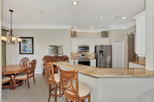 kitchen with ornamental molding, white cabinetry, appliances with stainless steel finishes, light stone countertops, and kitchen peninsula