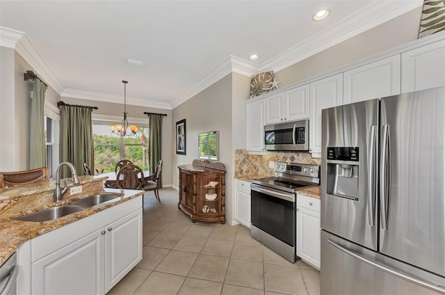 kitchen with light stone counters, stainless steel appliances, a notable chandelier, sink, and white cabinets