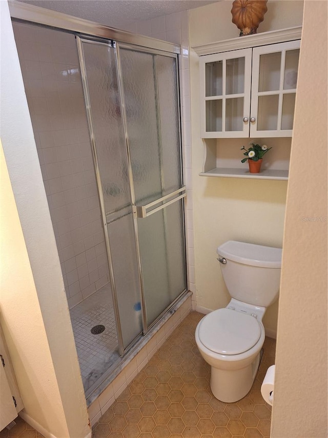 bathroom featuring toilet, tile patterned floors, and a shower with shower door