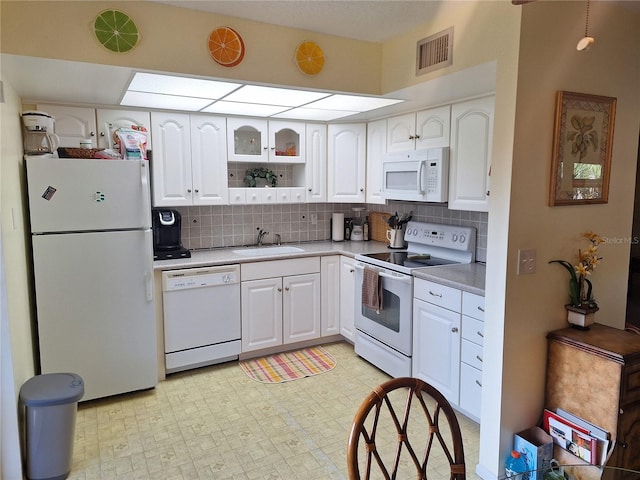 kitchen featuring decorative backsplash, white cabinetry, sink, and white appliances