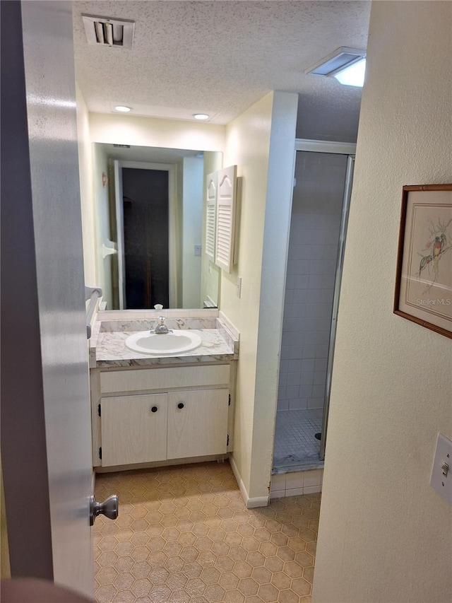 bathroom with vanity, walk in shower, and a textured ceiling