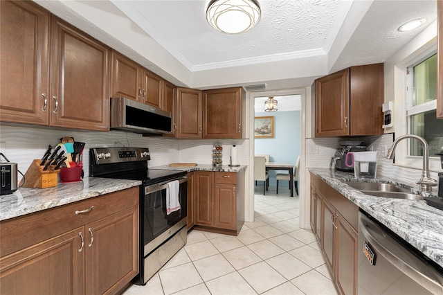 kitchen featuring appliances with stainless steel finishes, a textured ceiling, light stone countertops, and sink