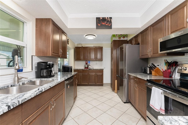 kitchen with light stone countertops, appliances with stainless steel finishes, sink, a textured ceiling, and ornamental molding