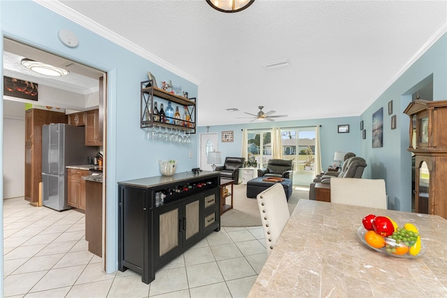 kitchen featuring crown molding, light tile patterned floors, a textured ceiling, stainless steel refrigerator, and ceiling fan