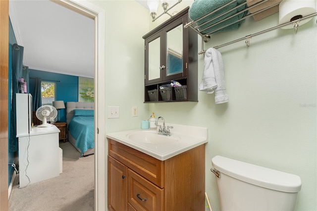 bathroom featuring toilet, crown molding, and vanity