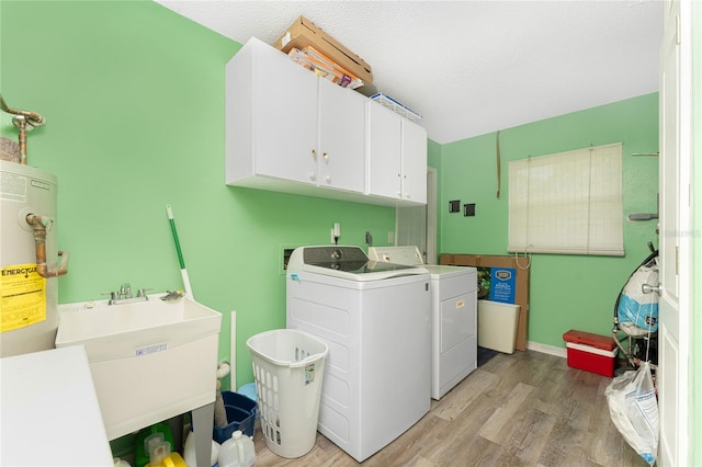 laundry room with sink, separate washer and dryer, a textured ceiling, light hardwood / wood-style floors, and cabinets