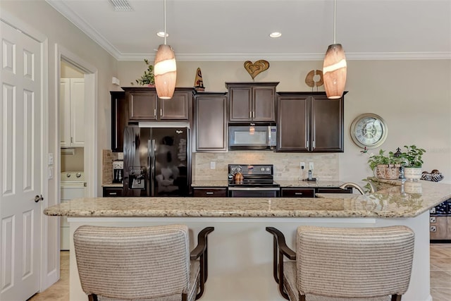 kitchen with black appliances, dark brown cabinets, a kitchen breakfast bar, hanging light fixtures, and a kitchen island with sink