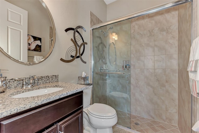 bathroom with a shower with door, vanity, toilet, and tile patterned flooring