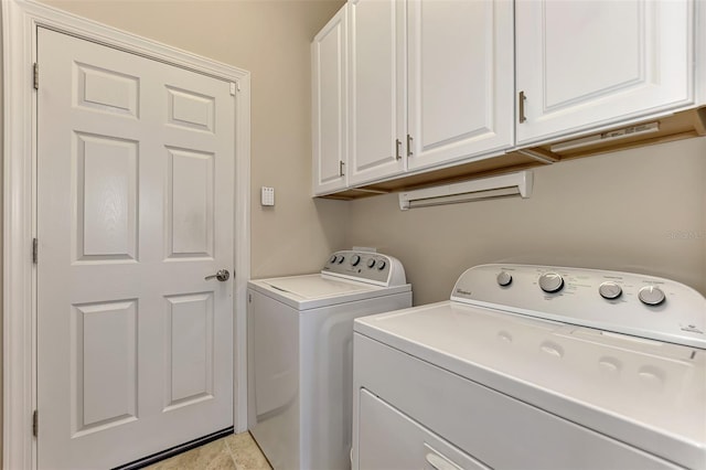 washroom with light tile patterned floors, cabinets, and washer and clothes dryer