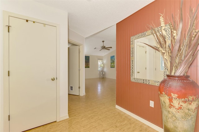 hall with light hardwood / wood-style flooring and a textured ceiling