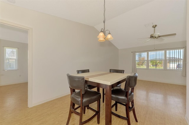 dining room featuring light hardwood / wood-style flooring, vaulted ceiling, and ceiling fan with notable chandelier